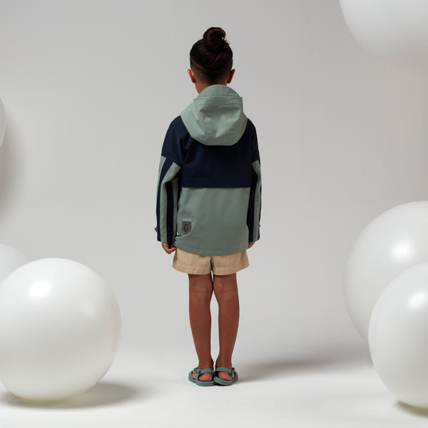 Lichtgroene uniseks regenjas 'Roaring Cat' van Gosoaky met kap en reflecterende strip. | Verkrijgbaar bij Little Fashion Addict