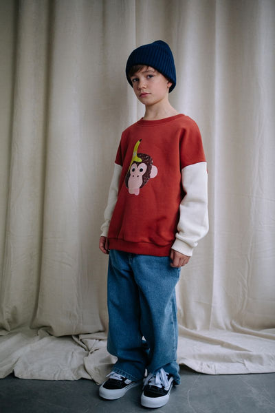 Bruine jongenssweater Funky Kong van Daily Brat met ecrukleurige mouwen en een speelse aap met banaanprint op de voorkant. 