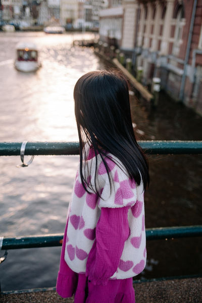 Witte teddy bodywarmer voor meisjes van Daily Brat met roze hartjes, ideaal om te dragen over jurkjes of truien. | Ontdek Daily Brat bij Little Fashion Addict