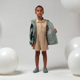 Lichtgroene uniseks regenjas 'Roaring Cat' van Gosoaky met kap en reflecterende strip. | Verkrijgbaar bij Little Fashion Addict