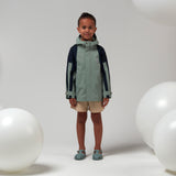 Lichtgroene uniseks regenjas 'Roaring Cat' van Gosoaky met kap en reflecterende strip. | Verkrijgbaar bij Little Fashion Addict