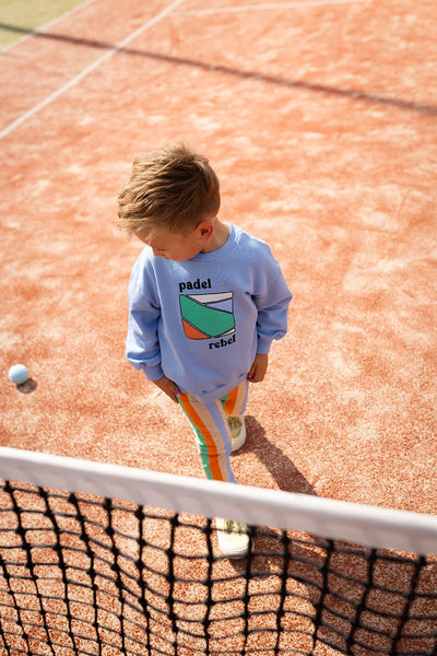 Jong kind draagt blauwe Padel Rebel sweater van Sproet & Sprout op sportveld | Sweatshirt Padel Rebel Forever Blue uit de Champions League of Fun Collectie